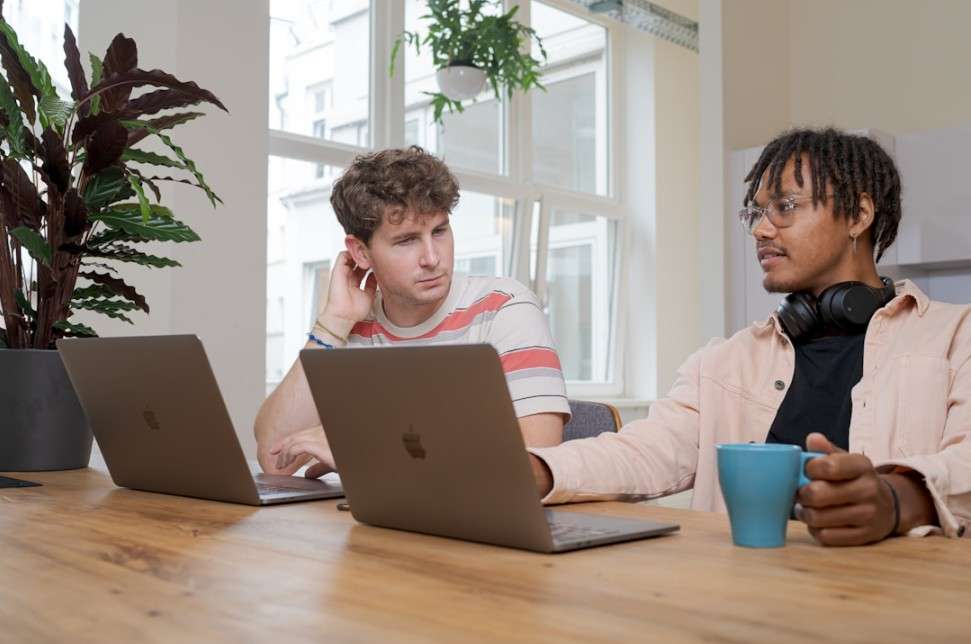 Two men collaborating at a table, each with a laptop, focused on a strategic account planning template.